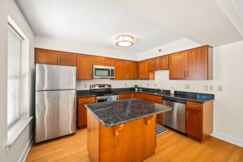 A kitchen with wooden cabinets and a granite counter top.